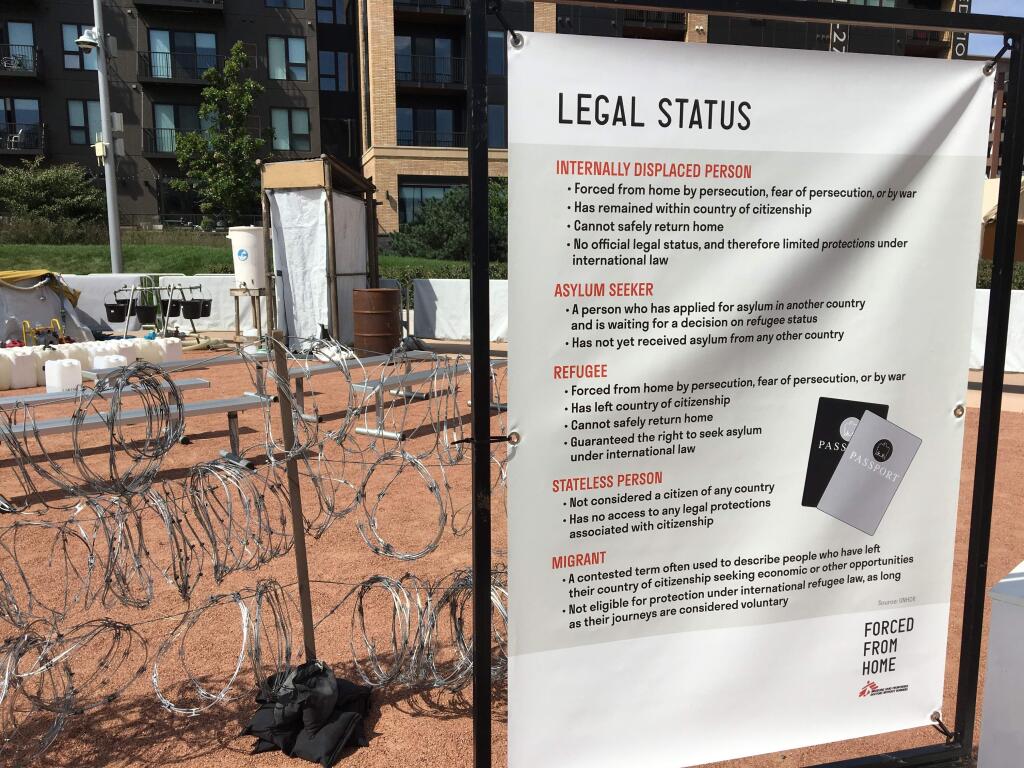 A sign with descriptions of legal status is shown with barbed wire in the background at a Minneapolis exhibition on the global refugee crisis. Secretary of State Mike Pompeo announced plans to lower the cap on the number of refugees allowed to resettle in the United States. (JEFF BAENEN / Associated Press)