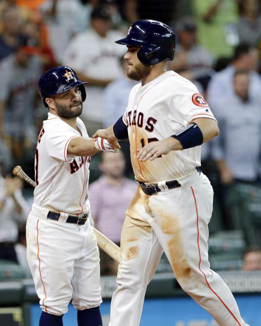 Houston Astros' Jose Altuve, left, congratulates Max Stassi (12) after he scores the go ahead run on the single by George Springer, making the score 4-3 during the fourth inning of a baseball game against the Oakland Athletics Wednesday, Aug. 29, 2018, in Houston. (AP Photo/Michael Wyke)