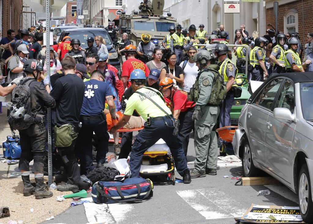 Rescue personnel help injured people after a car ran into a large group of protesters after an white nationalist rally Saturday in Charlottesville, Virginia. (STEVE HELBER / Associated Press)