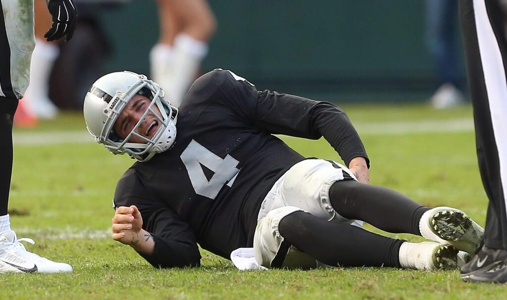 Oakland Raiders quarterback Derek Carr goes to the ground in pain after recovering a fumble in the third quarter against the Buffalo Bills in Oakland on Sunday, December 21, 2014. The Raiders defeated the Bills 26-24.(Christopher Chung/ The Press Democrat)