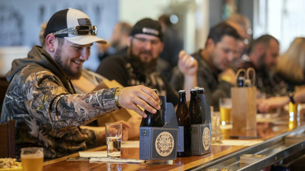Logan Jackson of San Jose lines up his take home bottles Pliny the Younger triple IPA for a photo at the Russian River Brewery in Windsor. (photo by John Burgess/The Press Democrat)