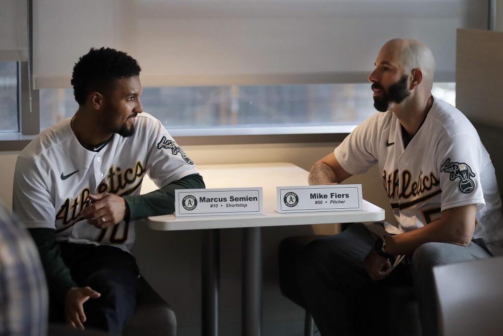 Oakland Athletics pitcher Mike Fiers, right, speaks with shortstop Marcus Semien prior to an interview with the media on Friday, Jan. 24, 2020, in Oakland. Fiers, the Oakland pitcher and whistleblower in the Houston Astros sign-stealing scandal, appeared with teammates and manager Bob Melvin at team offices. Fiers has not spoken publicly about the sign stealing since the story was published in the Athletic in November. (AP Photo/Ben Margot)
