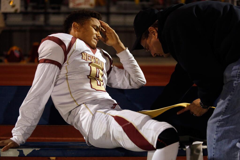 Cardinal Newman's Damian Wallace (8) grimaces as Dr. Mike McDermott puts a brace around his leg during the first half of the NCS Division 4 championship football game between Cardinal Newman and Marin Catholic high schools in Rohnert Park on Saturday, December 5, 2015. (Alvin Jornada / The Press Democrat)