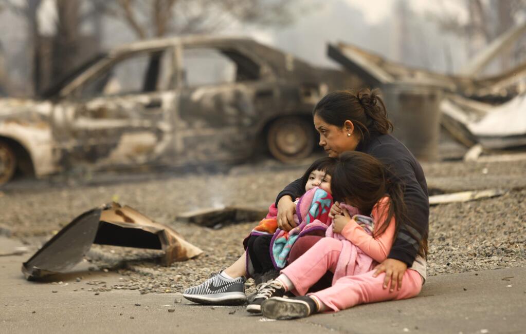 Liliana Contreras-Salgado sits with her daughters Gloria, 2, left, and Fatima, 6, in front of where their home used to be before it was destroyed by fire in Santa Rosa, on Monday, October 9, 2017. (BETH SCHLANKER/ The Press Democrat)