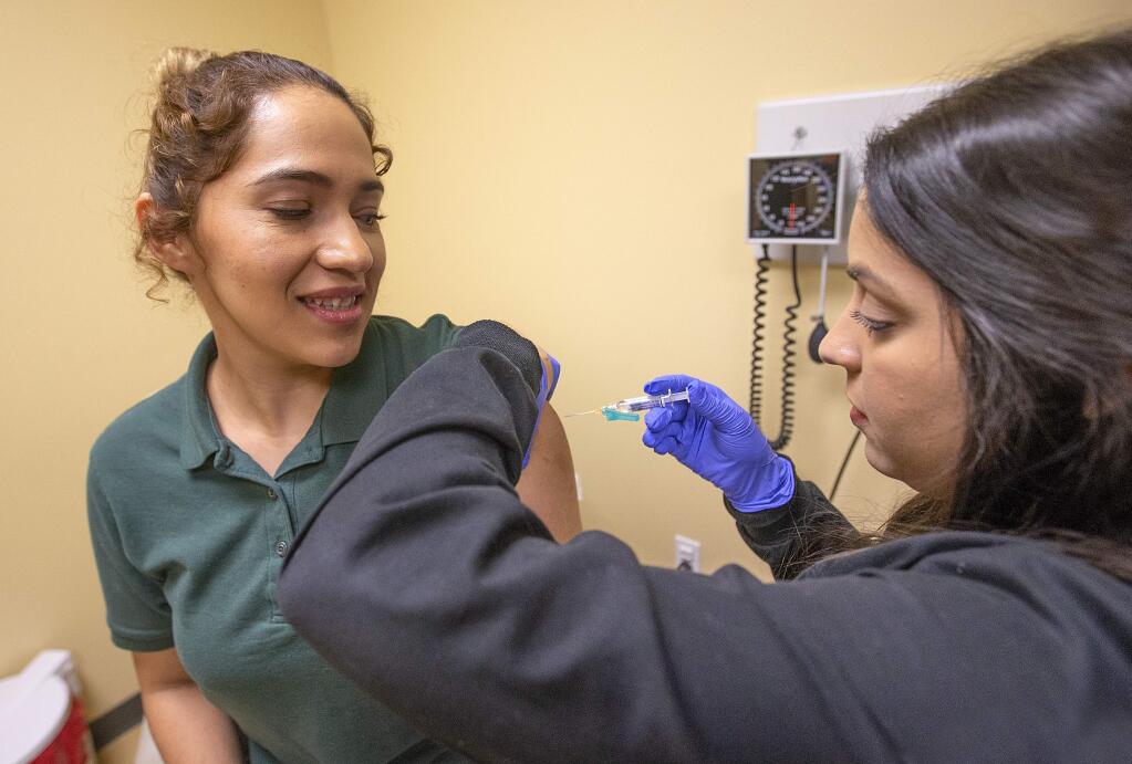 Medical assistant Nicole Goff gives a flu shot to patient Jennifer Flores at the Santa Rosa Community Health Center Airway Campus on Wednesday, Jan. 9, 2019. (JOHN BURGESS/ PD)