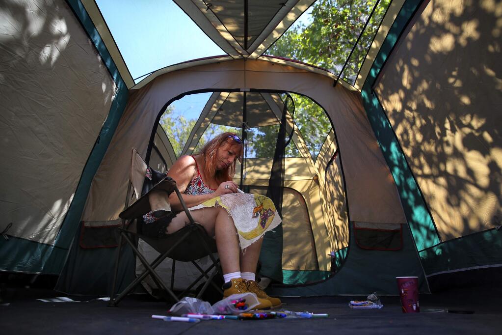 Nickalena Lonefight works on a piece of artwork for the homeless encampment, dubbed Camp Michela, which has sprouted on the county-owned property that was formerly the Sonoma County Water Agency site on College Avenue, in Santa Rosa, on Tuesday, September 8, 2015. Lonefight has been homeless for 20 years.(Christopher Chung/ The Press Democrat)