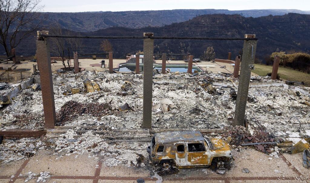 FILE - In this Dec. 3, 2018, file photo, a vehicle rests in front of a home leveled by the Camp fire in Paradise, Calif. (AP Photo/Noah Berger, File)