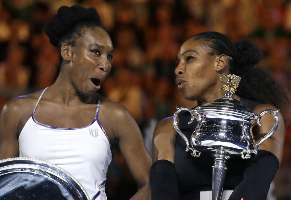 United States' Serena Williams, right, and her sister, Venus, chat, holding their trophies after Serena won the women's singles final at the Australian Open tennis championships in Melbourne, Australia, Saturday, Jan. 28, 2017. (AP Photo/Aaron Favila)
