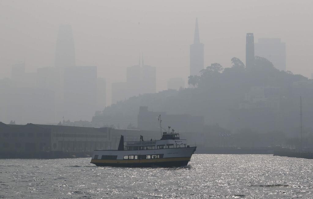 The skyline is obscured by smoke and haze from wildfires as a tour boat makes its way along the waterfront Thursday, Nov. 15, 2018, in San Francisco. Recurring wildfires are sparking concern among medical experts about potentially major health consequences. Worsening asthma, lung disease and even heart attacks in heart disease patients have all been linked with previous fires. But blazes that used to be seasonal are happening nearly year-round and increasingly spreading into cities. That's exposing many more people to choking smoke that contains many of the same toxic ingredients as urban air pollution. (AP Photo/Eric Risberg)
