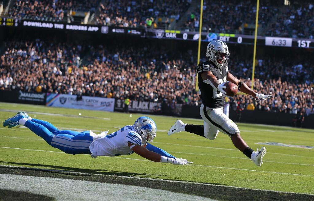 Oakland Raiders running back Josh Jacobs evades Detroit Lions safety Miles Killebrew to score a touchdown during their game in Oakland on Sunday, November 3, 2019. (Christopher Chung/ The Press Democrat)