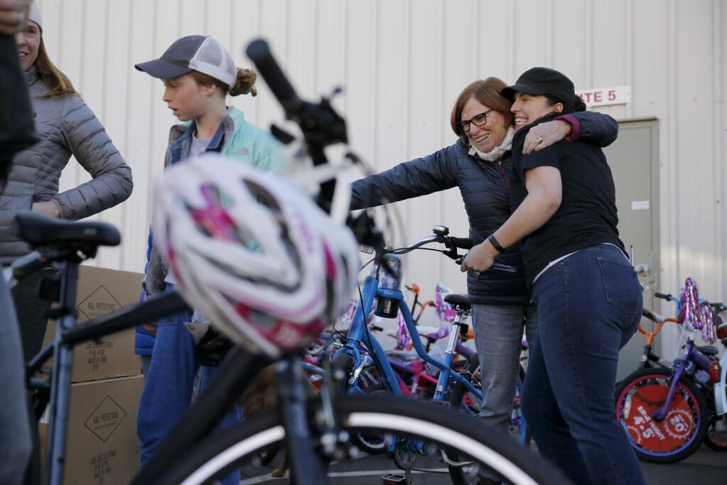Glen Ellen resident and fire victim Lauri Dorman embraces Carolyn Thompson, right, the co-owner of Bicycle Brustop, after receiving a bike that Thompson built, during a bicycle giveaway event on Sunday, December 10, 2017 in Sonoma, California . (BETH SCHLANKER/The Press Democrat)