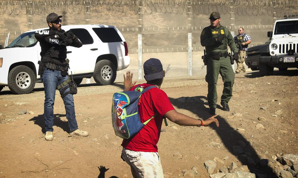 ALTERNATIVE CROP OF XRE301.- A Central American migrant is stopped by U.S. agents who order him to go back to the Mexican side of the border, after a group of migrants got past Mexican police at the Chaparral crossing in Tijuana, Mexico, Sunday, Nov. 25, 2018, at the border with San Ysidro, California. The mayor of Tijuana has declared a humanitarian crisis in his border city and says that he has asked the United Nations for aid to deal with the approximately 5,000 Central American migrants who have arrived in the city. (AP Photo/Pedro Acosta)APTOPIX