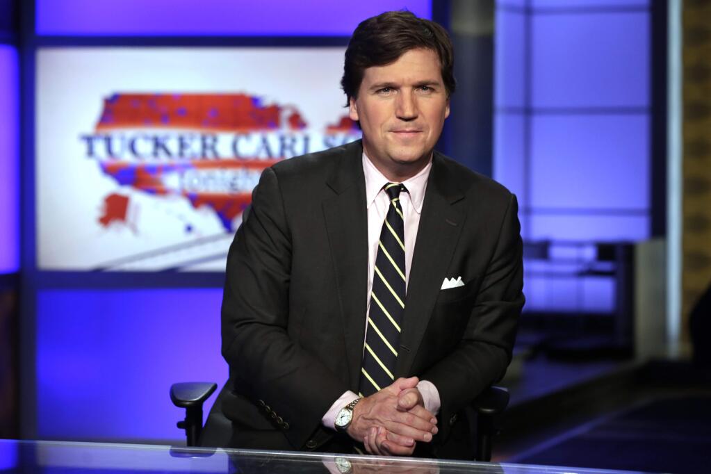 FILE - In this March 2, 2017, file photo, Tucker Carlson, host of 'Tucker Carlson Tonight,' poses for photos in a Fox News Channel studio in New York. Some advertisers say they are leaving conservative host Carlson's show following his remarks referring to immigrants as “the world's poor.” It's the latest example of sponsors leaving a Fox News Channel show after controversy, but experts say the flap is likely to blow over. So far, the biggest advertisers are sticking with him and his show, “Tucker Carlson Tonight.” (AP Photo/Richard Drew, File)