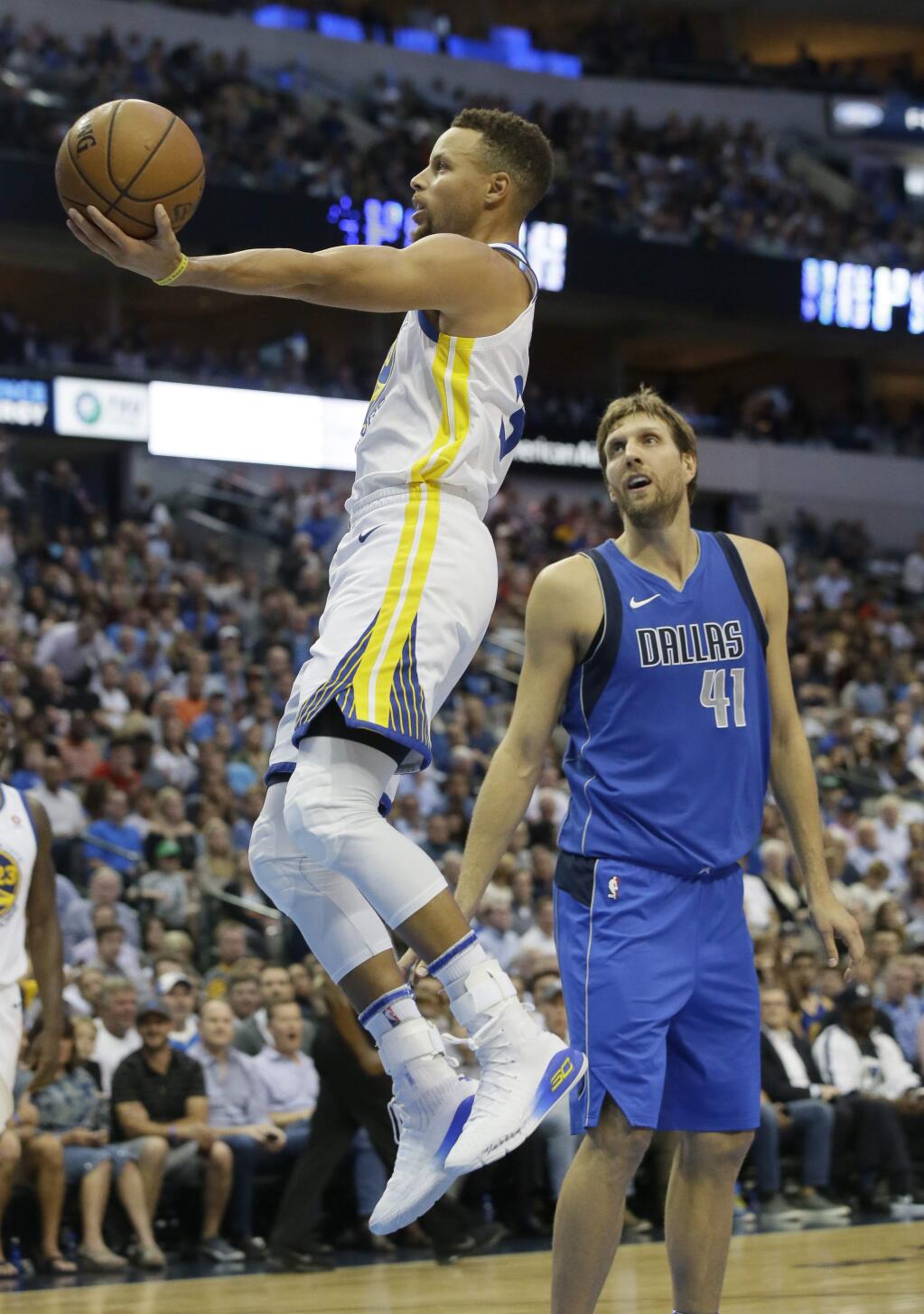 Golden State Warriors guard Stephen Curry, left, shoots past Dallas Mavericks forward Dirk Nowitzki (41) of Germany during the first half of an NBA basketball game in Dallas, Monday, Oct. 23, 2017. (AP Photo/LM Otero)