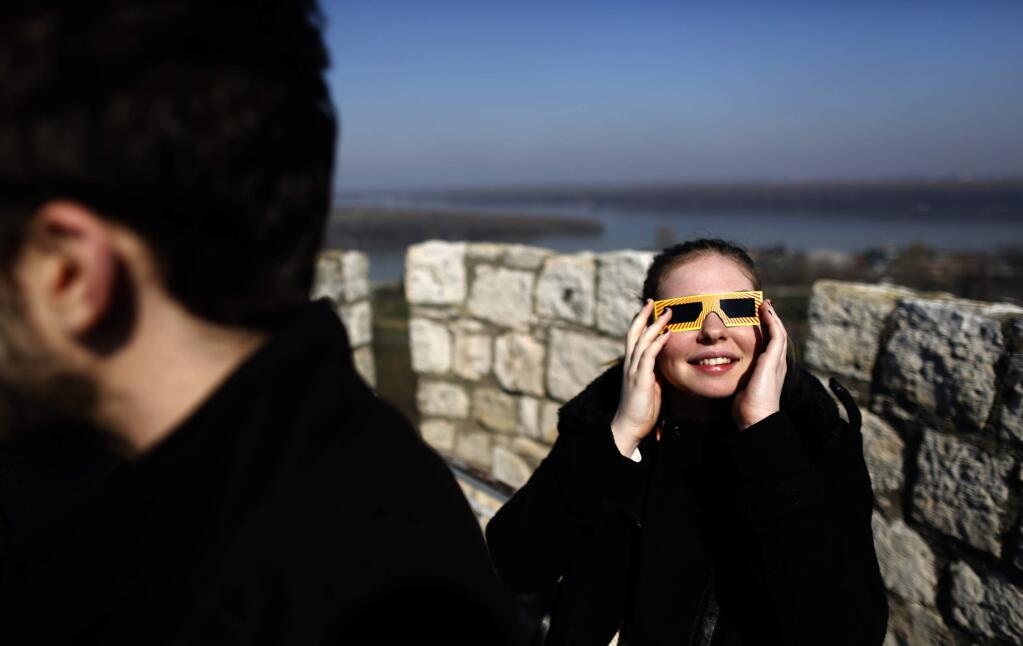 A girl watches the partial solar eclipse through goggles at citadel Kalemegdan in Belgrade, Serbia, Friday, March 20, 2015. Clouds moving over the city allowed only brief views of the eclipse which in southern Europe was partial. (AP Photo/Darko Vojinovic)