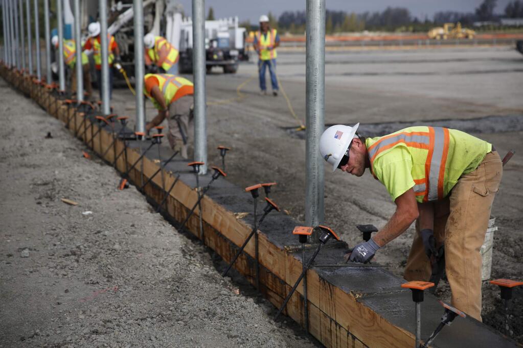 Jason Warren of Ghilotti Bros. Inc. smooths concrete for a curb and chain link fence at the new East Washington Park on Wednesday, September 17, 2014 in Petaluma, California. (BETH SCHLANKER/ The Press Democrat)