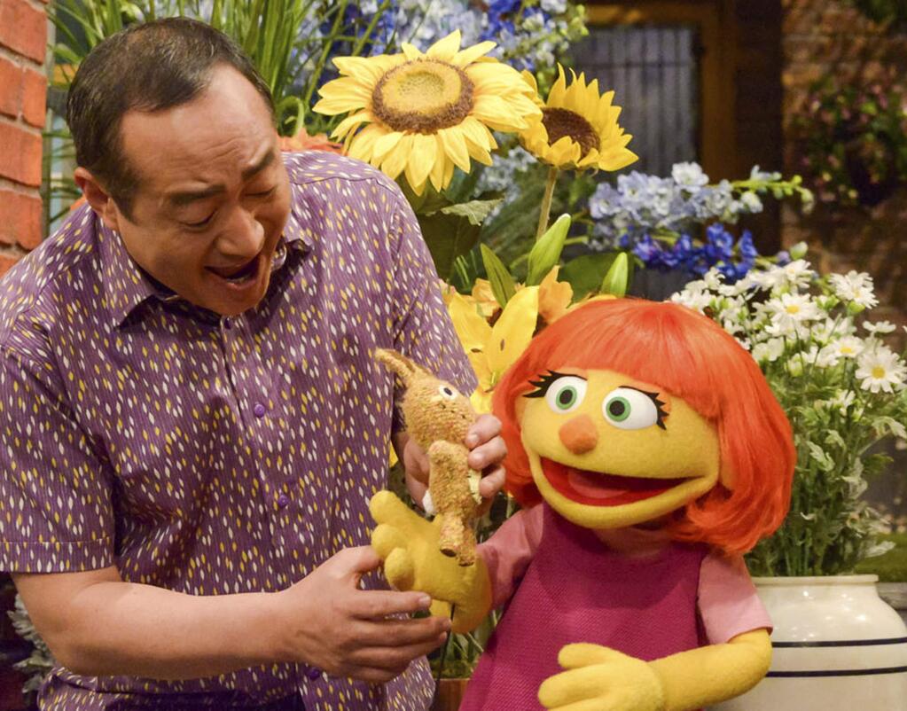 This image released by Sesame Workshop shows castmember Alan Muraoka, left, with Julia, an autistic muppet character debuting on the 47th Season of 'Sesame Street.' The popular children's TV show is celebrating its 50th season. (Zach Hyman/Sesame Workshop via AP)
