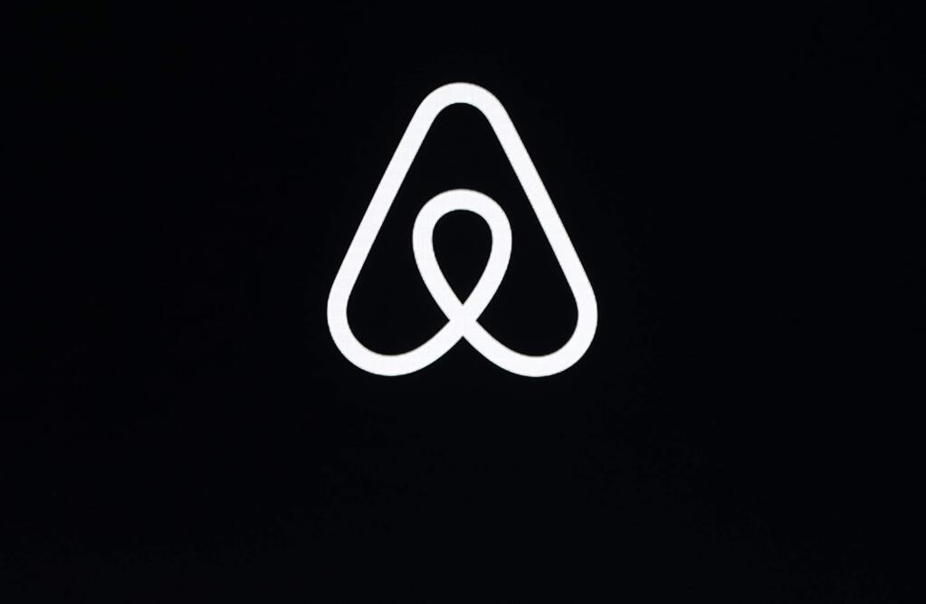 FILE - This Feb. 22, 2018, file photo shows an Airbnb logo during an event in San Francisco. A lucky few will be able to live the adventures of Phileas Fogg from Jules Vernes' classic 'Around the World in 80 Days.'Hosted by Airbnb, a small number of guests will travel across 16 countries to promote a new collection of available bookings called Airbnb Adventures. (AP Photo/Eric Risberg, File)
