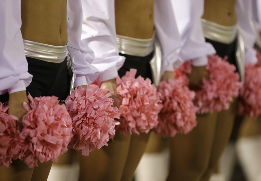 In this Oct. 6, 2013, file photo, Oakland Raiders cheerleaders hold pink pom-poms for breast cancer awareness before an NFL football game between the Raiders and the San Diego Chargers in Oakland, Calif. (AP Photo/Tony Avelar, File)