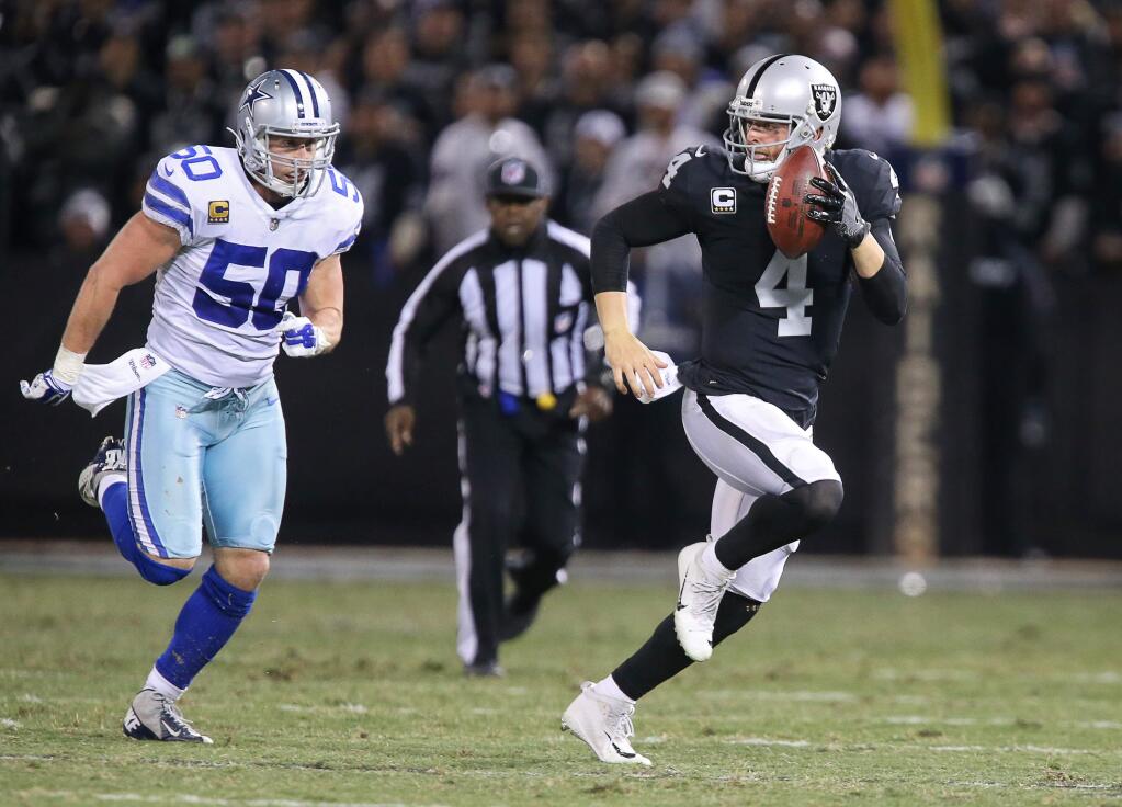 Oakland Raiders quarterback Derek Carr evades Dallas Cowboys linebacker Sean Lee as he runs for a 32-yard gain during their game in Oakland on Sunday, Dec. 17, 2017. The Raiders lost to the Cowboys 20-17. (Christopher Chung / The Press Democrat)