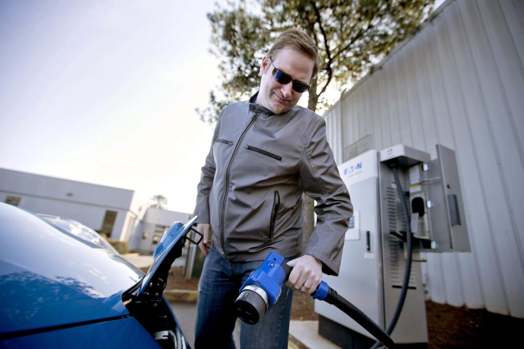 In this Thursday, Feb. 5, 2015 photo, Jason Marraccini, of Atlanta, recharges his Nissan electric vehicle at an auto dealership in Roswell, Ga. (AP Photo/David Goldman)