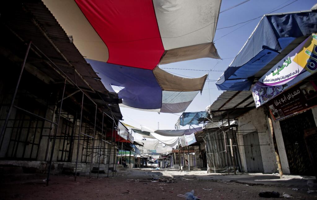 In this Friday, July 11, 2014 photo, shops are shuttered in a market that is usually bustling, due to Israeli attacks on the Gaza Strip, in Gaza City. (AP Photo/Khalil Hamra)