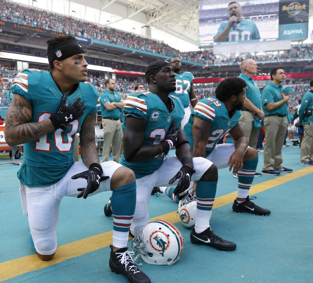 In this Sunday, Oct. 23, 2016, file photo, Miami Dolphins wide receiver Kenny Stills (10), free safety Michael Thomas (31) and defensive back Chris Culliver (29) kneel during the national anthem before the first half against the Buffalo Bills in Miami Gardens, Fla. (AP Photo/Wilfredo Lee, File)