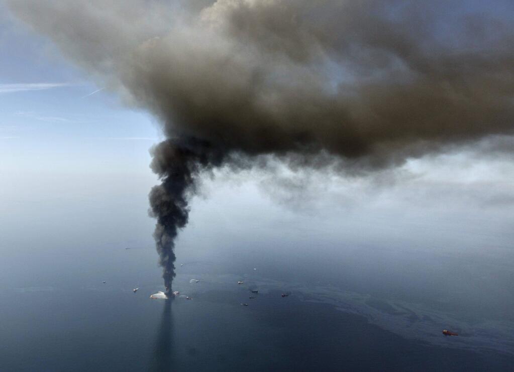 A large plume of smoke rising from BP's Deepwater Horizon offshore oil rig in the Gulf of Mexico following a blowout on April 20, 2010. (GERALD HERBERT / Associated Press).