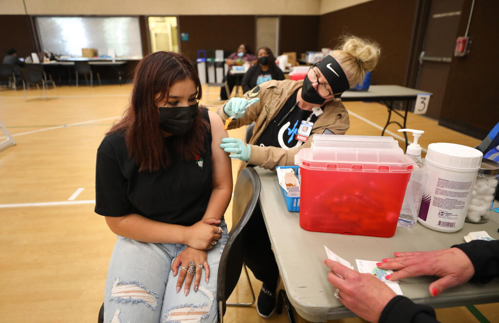Jennifer Perez, 14, receives her first dose of the Pfizer COVID-19 vaccine from nurse Kerri Teague at the Alliance Medical Center vaccination clinic at Huerta Gymnasium in Windsor on Friday, May 28, 2021.  (Christopher Chung/ The Press Democrat)