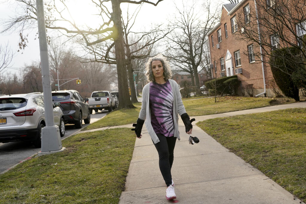 Catherine Busa takes a walk around her neighborhood as part of her recovery from COVID-19 in New York, Wednesday, Jan. 13, 2021. The 54-year-old New York City school secretary didn’t have any underlying health problems when she caught the coronavirus in March and recovered at her Queens home. But some symptoms lingered. After eights months of suffering, she made her way to Jamaica Hospital Medical Center — to a clinic specifically for post-COVID-19 care. (AP Photo/Seth Wenig)