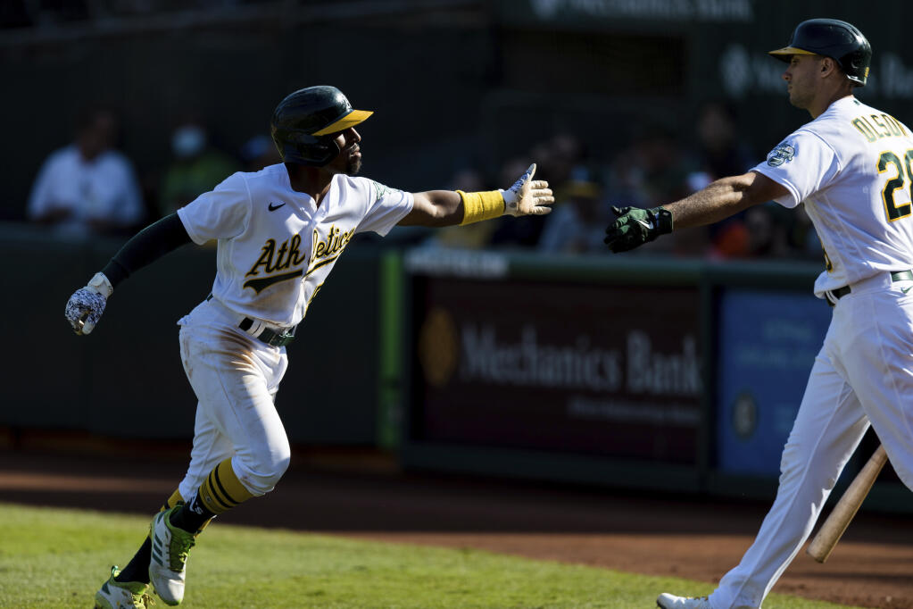 Oakland Athletics' Tony Kemp, left, celebrates with Matt Olson after scoring a run against the Houston Astros in the seventh inning of a baseball game in Oakland, Calif., Sunday, Sept. 26, 2021. (AP Photo/John Hefti)