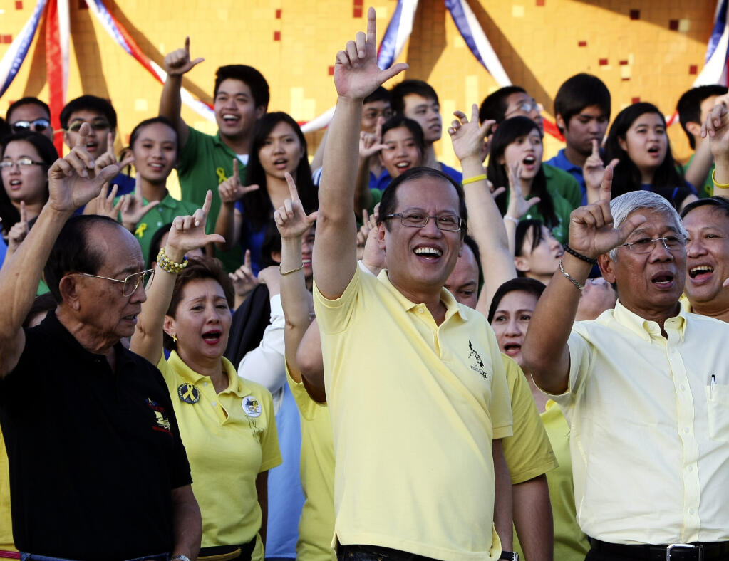CORRECTS DATE, FILE - In this Feb. 25, 2011, file photo, Philippine President Benigno Aquino III, center, former President Fidel Ramos, left, and Defense Chief Voltaire Gazmin, flash the "L" sign (for Laban which means Fight!) during the celebration of the 25th anniversary of the People Power revolution at the People Power Monument along EDSA highway at suburban Quezon city northeast Manila, Philippines. Aquino, the son of pro-democracy icons who helped topple dictator Ferdinand Marcos and had troublesome ties with China, died Thursday, June 24, 2021, a cousin and public officials said. (AP Photo/Bullit Marquez, File)