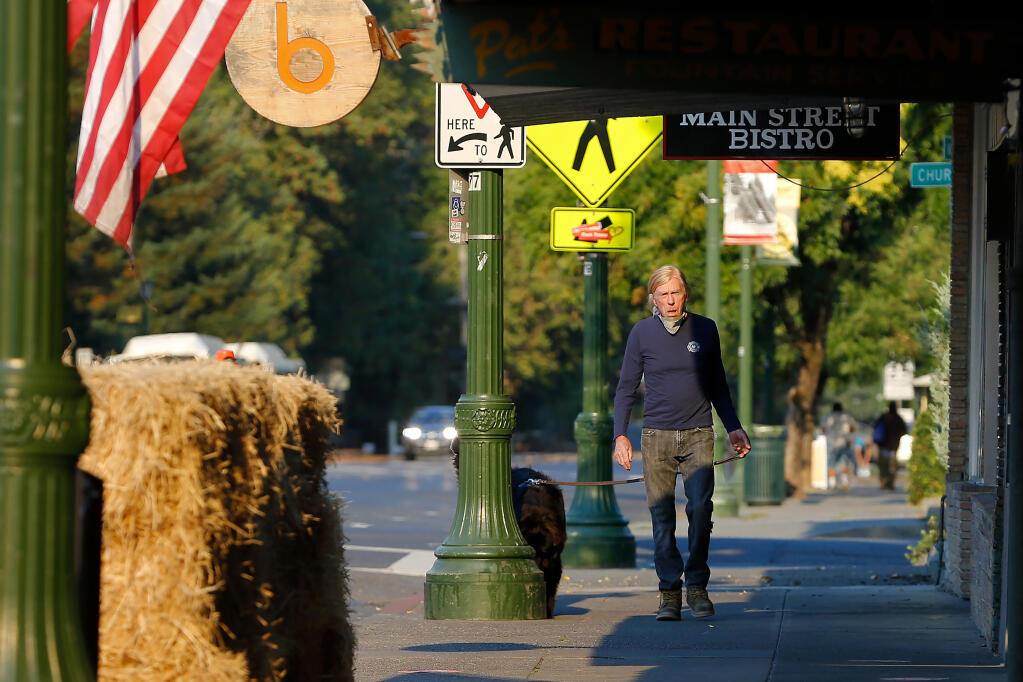 Guerneville resident Wendell Joost, who said he has been through four wildfires and seven floods in the 43 years he has lived in town, walks his dog Jupiter along Main Street after mandatory evacuation orders were made due to the Walbridge fire in Guerneville on Wednesday, Aug. 19, 2020. (Alvin A.H. Jornada / The Press Democrat)