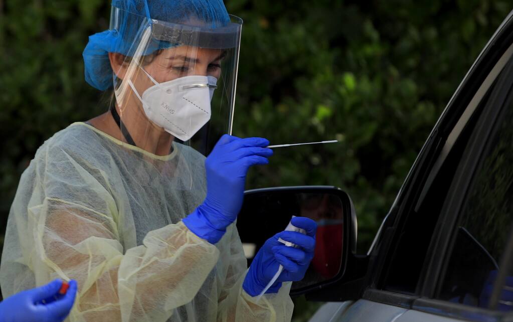 Paula Pelavin, a physicians assistant, prepares to obtain a swab sample during drive up COVID-19 testing at Petaluma Health Center, Tuesday, July 14, 2020. (Kent Porter / The Press Democrat) 2020