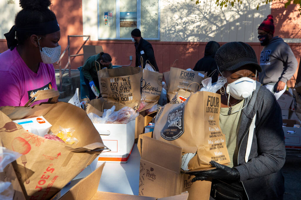 Sonoma County Black Forum board member Segretta Woodard, right, organizes boxes of food to be given out during a food distribution by the Sonoma County Black Forum in front of Santa Rosa High School on Nov. 21, 2020. (Alvin A.H. Jornada / The Press Democrat)