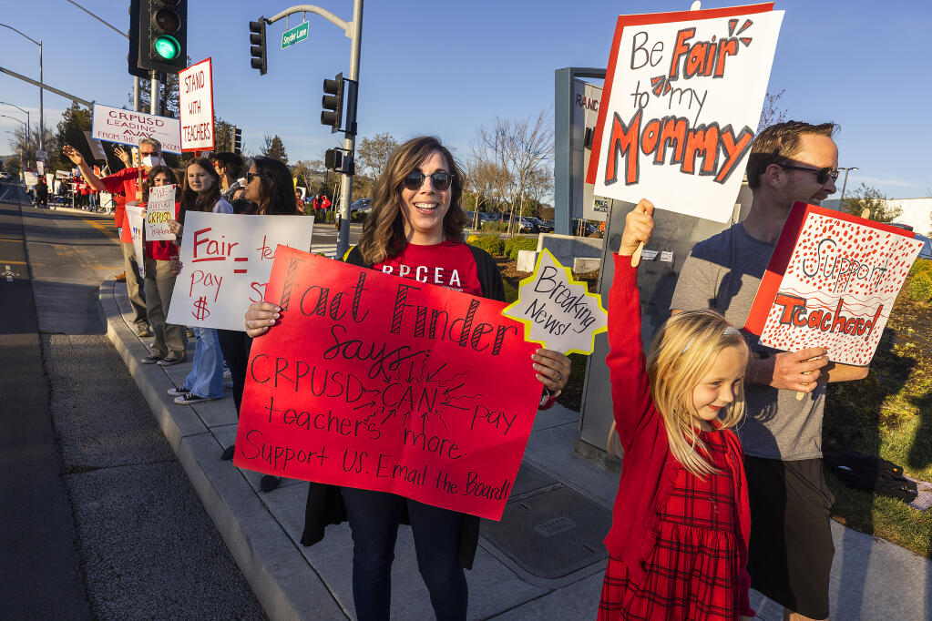 From right, Claire Wilcox, 7, joined her mom Cassandra, a kindergarten teacher at Monte Vista Elementary, in a protest for higher wages in front of Rancho Cotate High School where the school board was meeting on Tuesday, March 8, 2022.  (John Burgess / The Press Democrat)