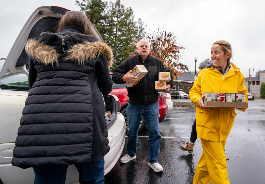 Volunteer Rachelle Mesheau, right, helps unload boxes of canned goods for the “Sleigh Hunger” food and funds drive at Courthouse Square on Saturday, Dec. 10, 2022 in Santa Rosa. (Nicholas Vides / For The Press Democrat)