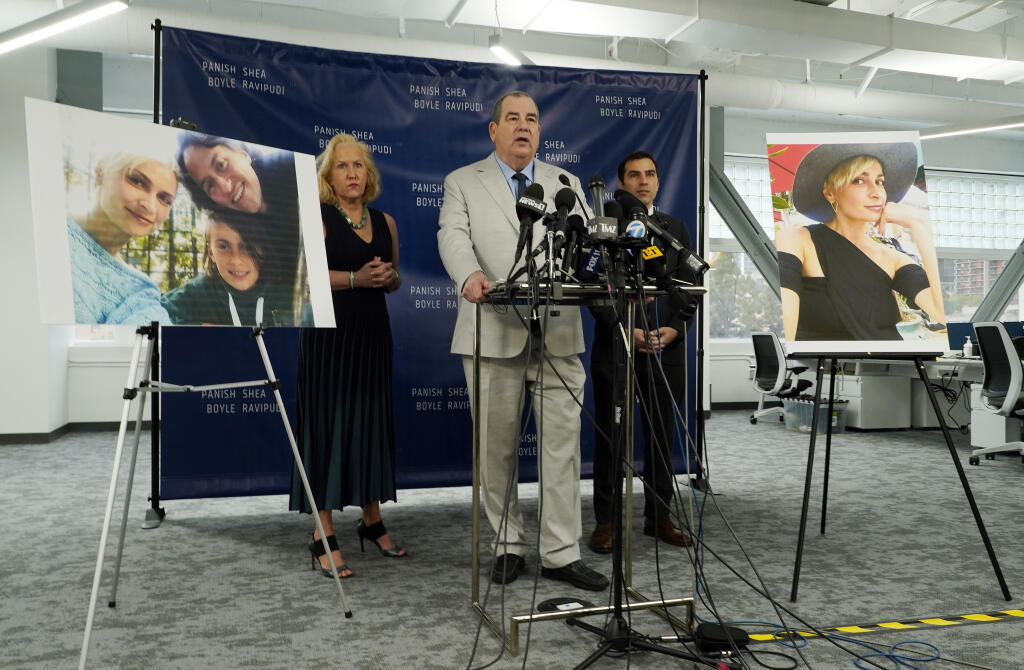Randi McGinn, from left, Brian Panish and Jesse Creed, attorneys for the family of cinematographer Halyna Hutchins, take part in a news conference alongside portraits of Hutchins and her family, Tuesday, Feb. 15, 2022, in Los Angeles. The family of Hutchins is suing Alec Baldwin and the movie producers of "Rust" for wrongful death, the attorneys said Tuesday. (AP Photo/Chris Pizzello)
