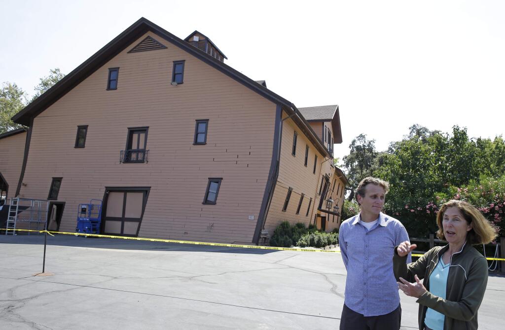 Owner Janet Trefethen, right, and president Jon Ruel, left, talk about the earthquake damage to the historic winery building, seen in the background, dating from 1886 at Trefethen Family Vineyards Monday, Aug. 25, 2014, in Napa, Calif. The winery is hopeful they can save the building after San Francisco Bay Area's strongest earthquake in 25 years struck the heart of California's wine country early Sunday. (AP Photo/Eric Risberg)