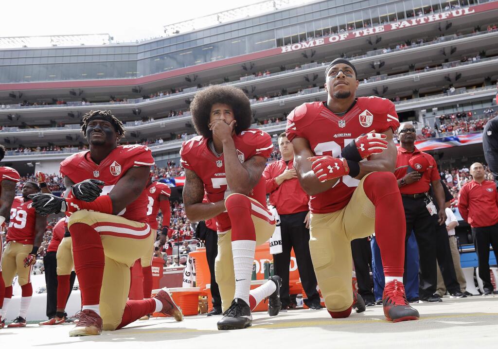 FILE - In this Oct. 2, 2016, file photo, from left, San Francisco 49ers outside linebacker Eli Harold, quarterback Colin Kaepernick and safety Eric Reid kneel during the national anthem before an NFL football game against the Dallas Cowboys in Santa Clara, Calif. During an appearance on Fox News Jan. 3, 2017, former Redskins quarterback Joe Theismann slammed the 49ers' decision to give Kaepernick an award for being an “inspirational and courageous” player. (AP Photo/Marcio Jose Sanchez, File)