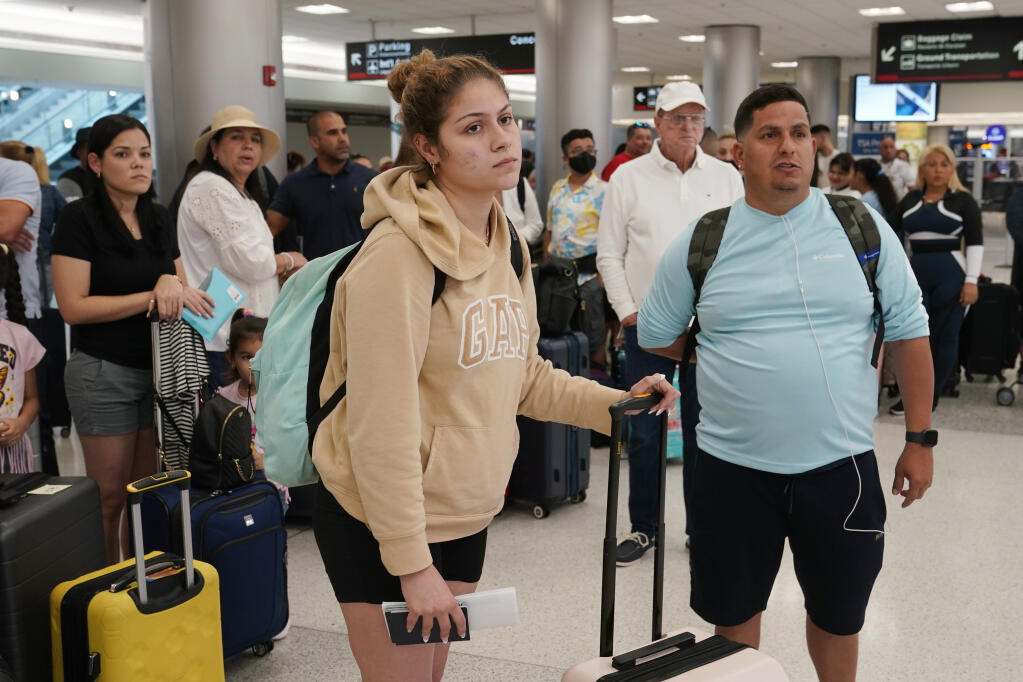 Mercedes and Jorge Herrera of Tampa, wait to check-in their luggage at Miami International Airport, Saturday, July 2, 2022, in Miami. The Herreras are flying to Punta Cana, Dominican Republic, for a family reunion. The Fourth of July holiday weekend is jamming U.S. airports with the biggest crowds since the pandemic began in 2020.(AP Photo/Marta Lavandier)