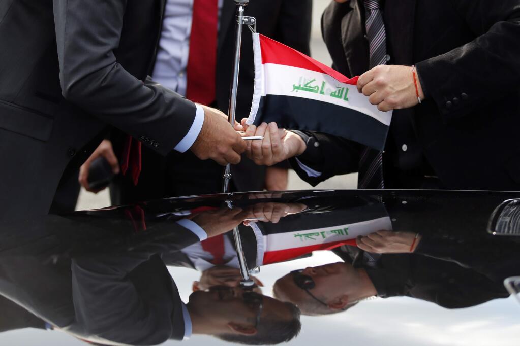 Officials install an Iraq flag on the car upon the arrival of Iraq President Fouad Massoum, and Iraq Foreign Minister Ibrahim Al-Jaafari at Orly airport south of Paris, France, Sunday, Sept. 14, 2014 ahead of a conference with U.S. Secretary of State John Kerry, French President Francois Hollande and diplomats from around the world. (AP Photo/Francois Mori)