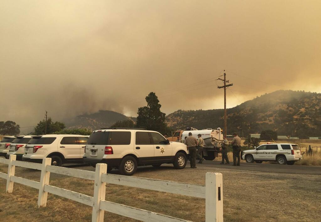 Merced and Mariposa County Sheriff's Office members gather during a wildfire in Mariposa County, Calif., Tuesday, July 18, 2017. Tall grass from a deluge of winter rains is fueling wildfires throughout the Western U.S., damaging more than a dozen homes in Nevada and threatening hundreds more structures in California. The California Department of Forestry and Fire Protection on Tuesday ordered evacuations for some residents living southwest of Yosemite National Park. (Merced County Sheriff's Office via AP)