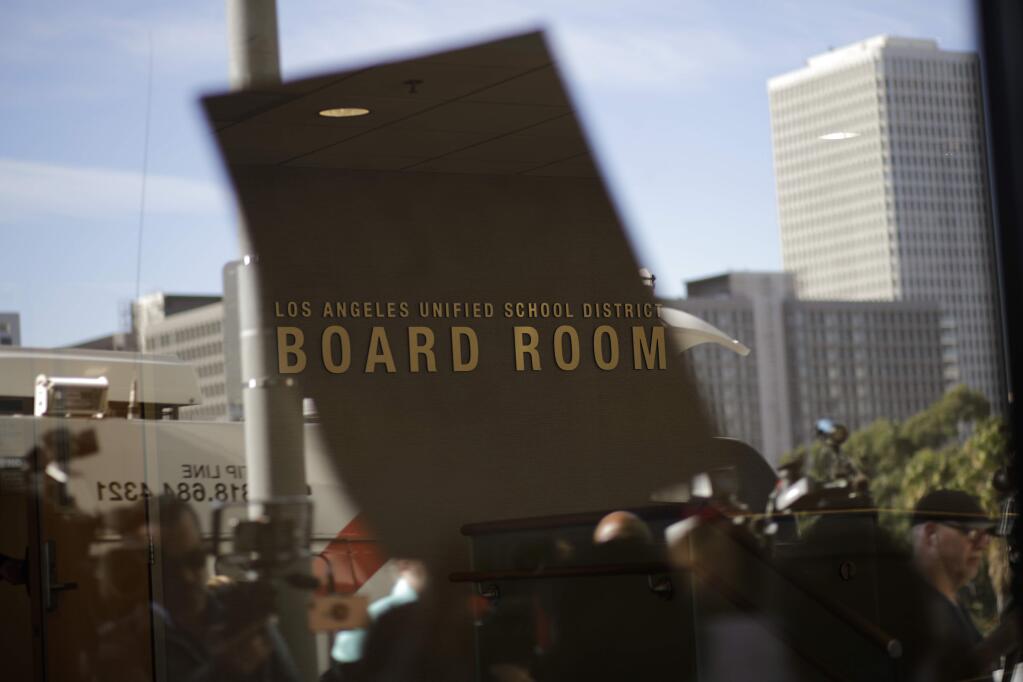 The Los Angeles Unified School District board room sign is seen through the window as parents and teachers gather for a news conference held outside the LAUSD headquarters Wednesday, Jan. 9, 2019, in Los Angeles, Calif. The union representing teachers in Los Angeles has postponed the start of a possible strike until Monday because of uncertainty over whether a judge would order a delay. (AP Photo/Jae C. Hong)