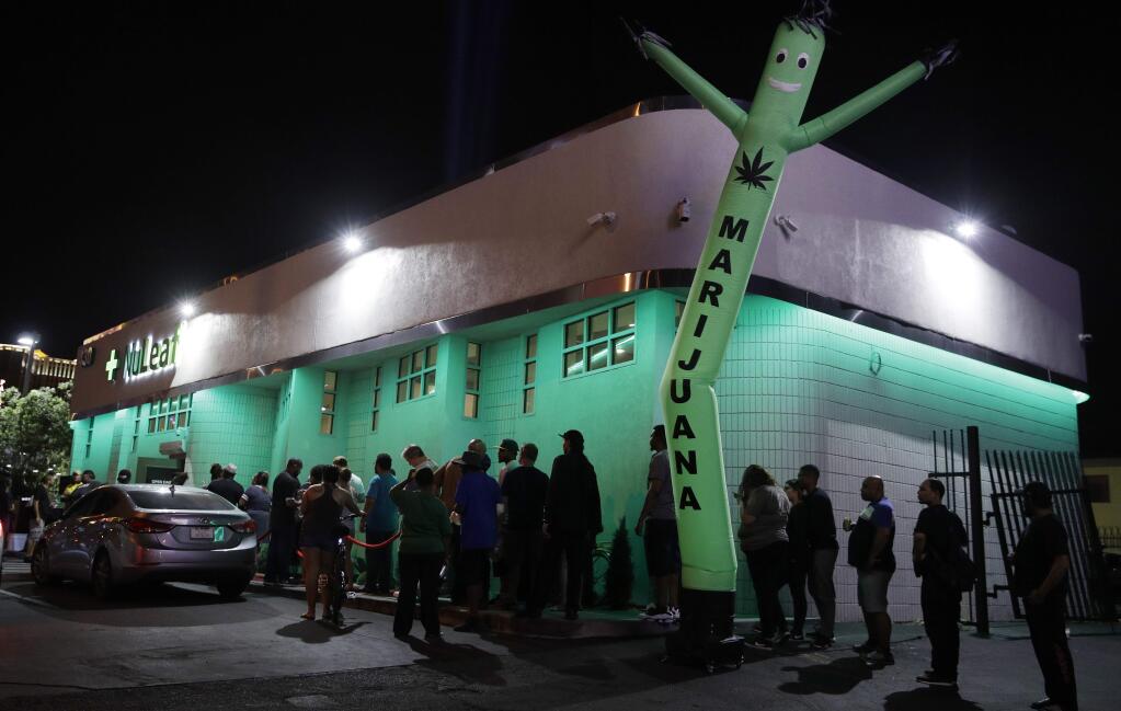 FILE- In this July 1, 2017, file photo, people line up at the NuLeaf marijuana dispensary in Las Vegas. A judge cleared the way Thursday, July 17, for Nevada to allow more businesses to move marijuana from growers to stores in an effort to keep up with overwhelming demand since recreational pot sales began last month. (AP Photo/John Locher, File)