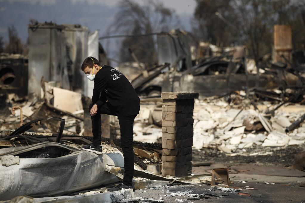 Benjamin Lasker, 16, pauses while looking at what remains of his home after a wildfire swept through Sunday, Oct. 15, 2017, in Santa Rosa, Calif. With the winds dying down, fire officials said Sunday they have apparently 'turned a corner' against the wildfires that have devastated California wine country and other parts of the state over the past week, and thousands of people got the all-clear to return home. (AP Photo/Jae C. Hong)