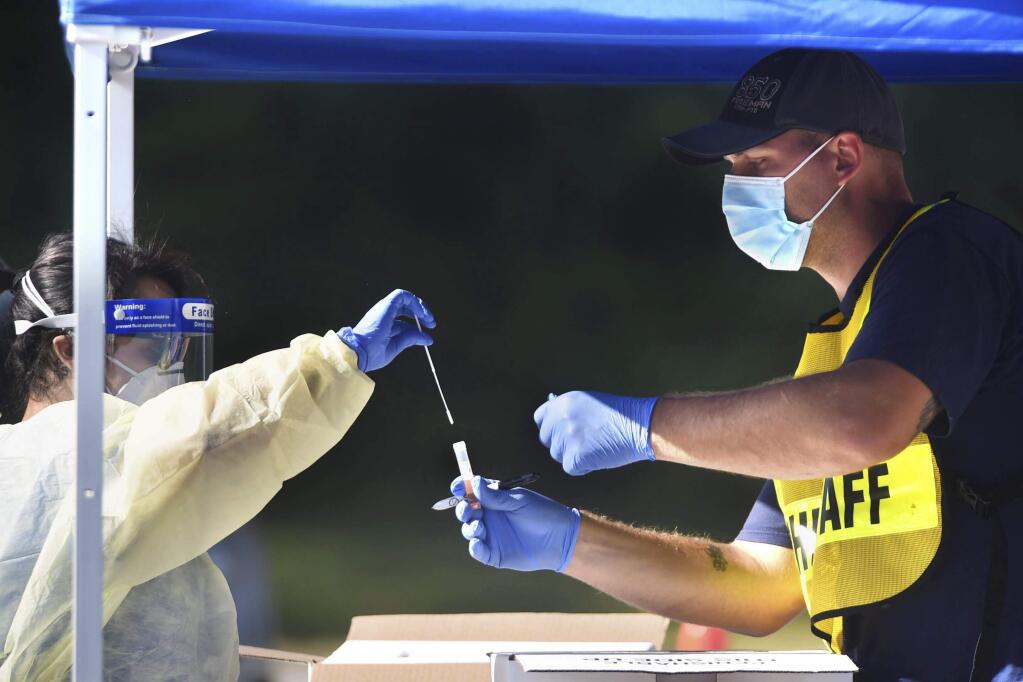 Medical personnel place a swab in a specimen container at a drive-thru COVID-19 testing site, Thursday, May 14, 2020 in Crestview, Fla. Officials in Florida panhandle's Okaloosa County have begun offering regular free drive-thru COVID-19 testing for county residents at various sites around Okaloosa County.(Devon Ravine/Northwest Florida Daily News via AP)
