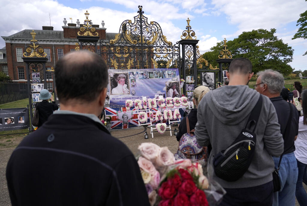 People line up to leave floral arrangements in remembrance of Princess Diana outside the gates of Kensington Palace, in London, Wednesday, Aug. 31, 2022. Wednesday marks the 25th anniversary of Princess Diana's death in a Paris car crash. (AP Photo/Alberto Pezzali)