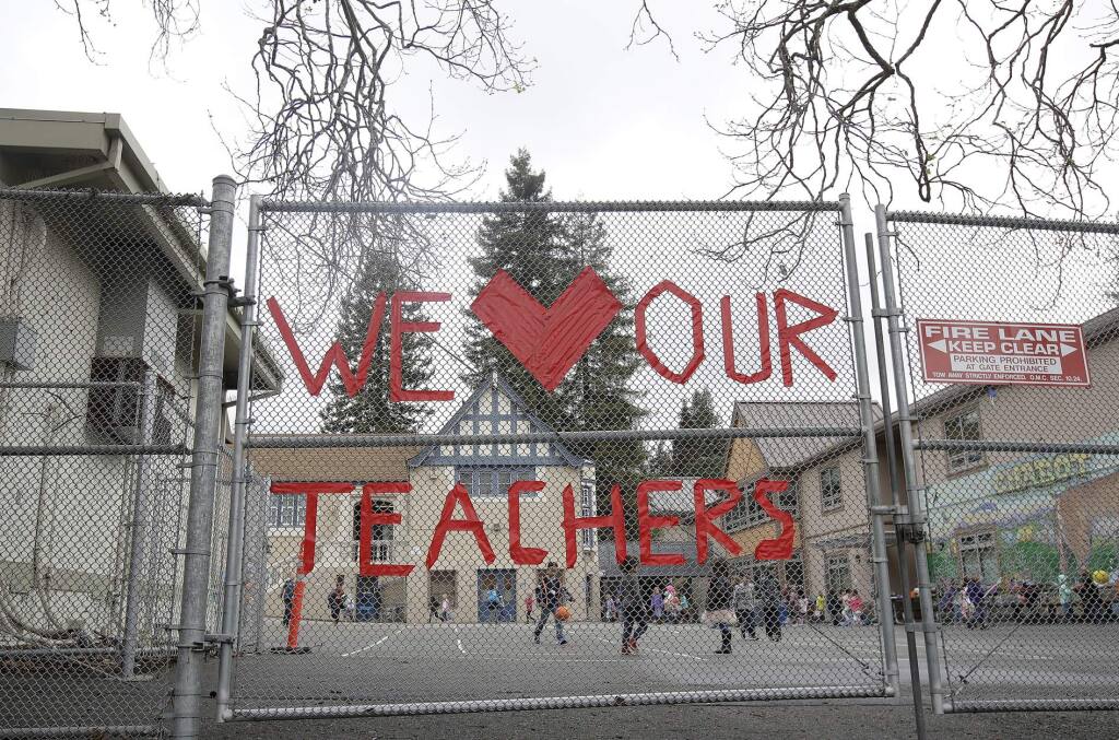 FILE - In this March 4, 2019, file photo, a sign supporting teachers is shown on a fence outside of Chabot Elementary School in Oakland, Calif. California Democratic Gov. Gavin Newsom presented a revised $203 billion budget proposal to state lawmakers Thursday, May 14, 2020, reflecting an economy and tax revenues hobbled by the coronavirus pandemic. . (AP Photo/Jeff Chiu, File)