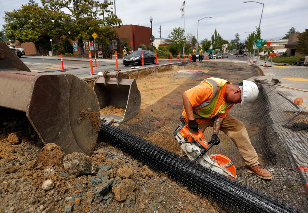 Laborer David Pulido of Team Ghilotti cuts away a sheet of geogrid stabilization fabric which will reinforce the soil once the street is paved, at the intersection of Bodega Avenue and High Street in Sebastopol, California, on Wednesday, June 7, 2017. (Alvin Jornada / The Press Democrat)